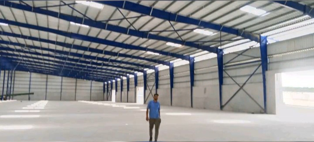 Charpente industrielle 20 000 m² à Yopougon PK24 : structure métallique bleue, pannes, portiques et couverture en cours de finition — vue 5