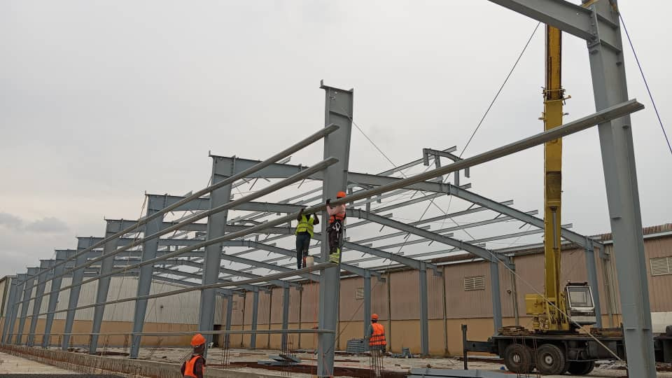 Charpente industrielle agroalimentaire 5 001 m² à Bonoua : bardage beige, structure métallique, couverture et montage en cours — vue 7