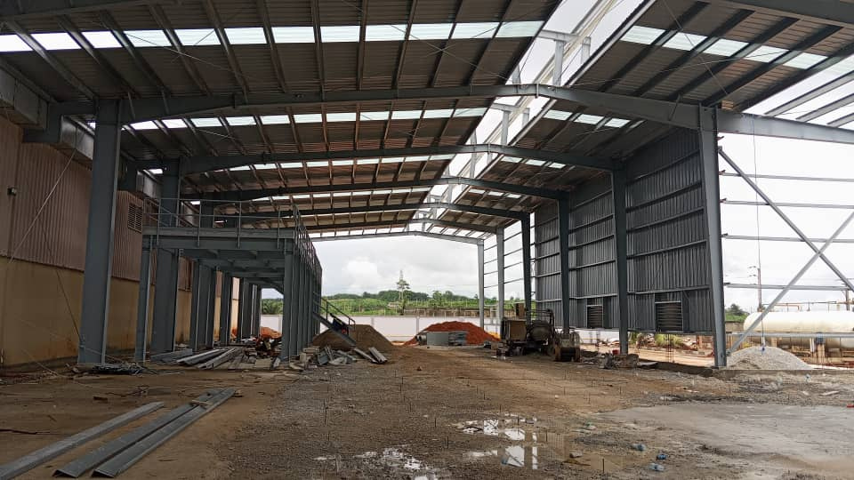 Charpente industrielle agroalimentaire 5 001 m² à Bonoua : bardage beige, structure métallique, couverture et montage en cours — vue 6