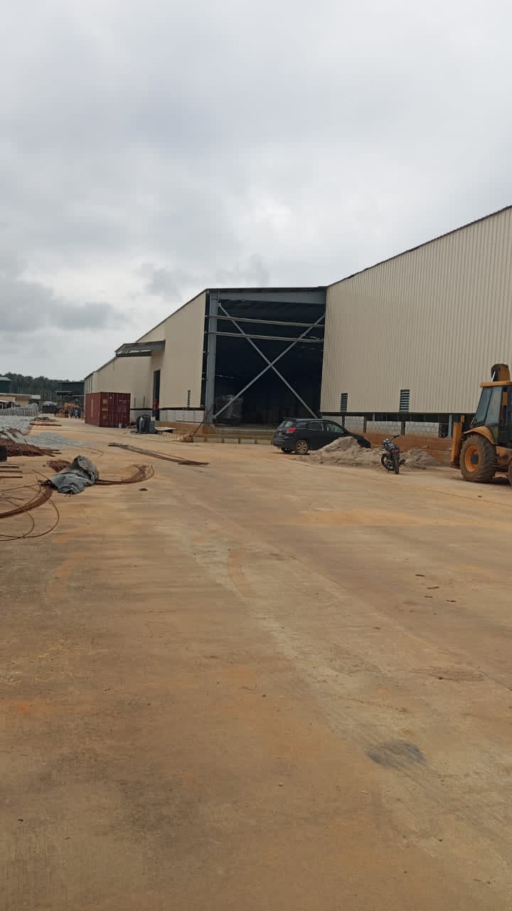 Charpente industrielle agroalimentaire 5 001 m² à Bonoua : bardage beige, structure métallique, couverture et montage en cours — vue 3